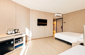 A hotel room with a bed, a TV mounted on the wall, a minibar, and a desk with a kettle and cups. - Ming Star Hotel (Kuala Terengganu)