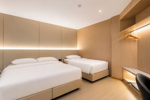 A modern hotel room with two beds, a wooden wardrobe, and a desk with a chair.