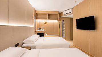 A hotel room with two beds, a TV, a minibar, and a mirror.