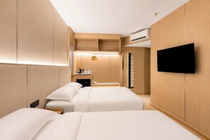 A hotel room with two beds, a TV, a minibar, and a mirror.
