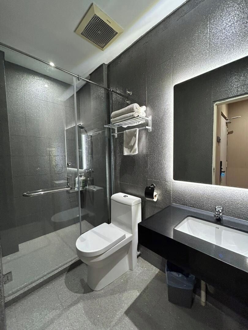 A modern bathroom with a glass-enclosed shower, a toilet, a sink, and a towel rack.