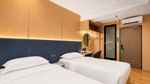 Una habitación de hotel con dos camas, un escritorio, un espejo y un armario.