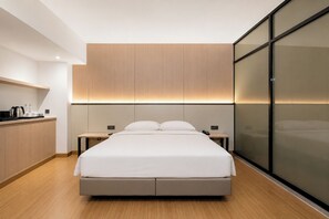 A modern hotel room with a large bed, bedside tables, a built-in wardrobe, and a glass partition. - Ming Paragon Hotel (Kuala Terengganu)