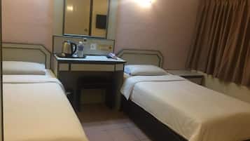 Une chambre d’hôtel avec deux lits simples, un bureau avec une chaise, un miroir et une lampe fixée au mur.