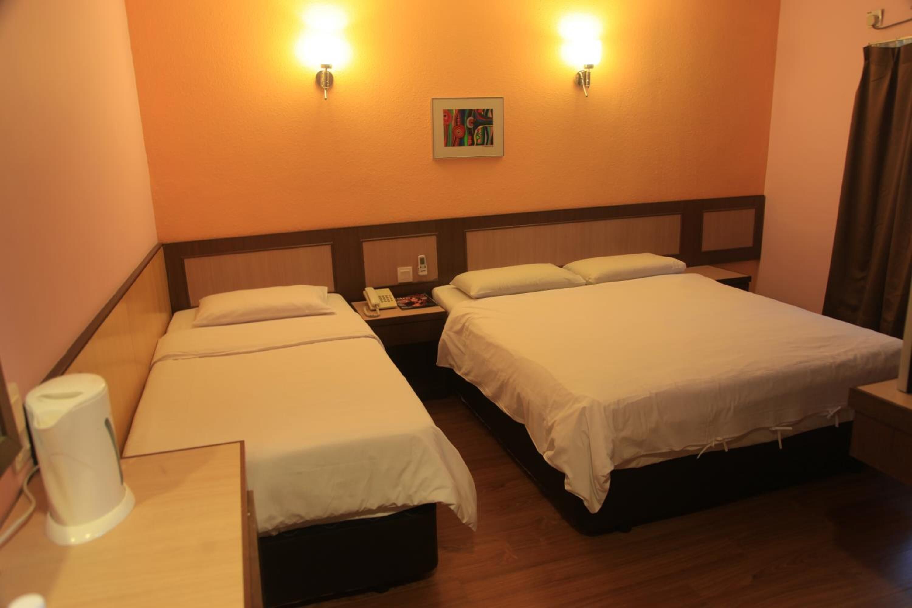 Habitación de hotel con dos camas, una mesita de noche con teléfono y un cuadro en la pared.