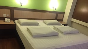 A hotel room with a bed, two pillows, a bedside table with a phone, and a wall-mounted light. - The Inn Hotel (Kuala Terengganu)