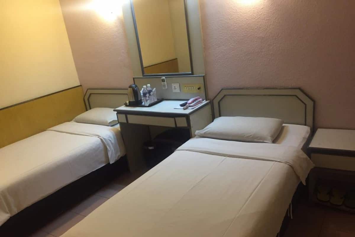 A hotel room with two single beds, a desk with a chair, a mirror, and a telephone.