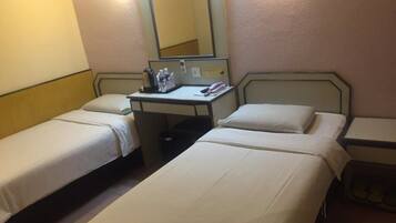 A hotel room with two single beds, a desk with a chair, a mirror, and a telephone.
