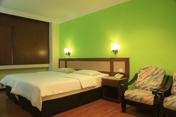A hotel room with a bed, two bedside lamps, a nightstand, and a chair.