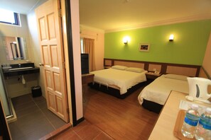 Une chambre d’hôtel avec deux lits, un bureau avec une machine à café, un miroir et une salle de bain avec un lavabo et des toilettes.