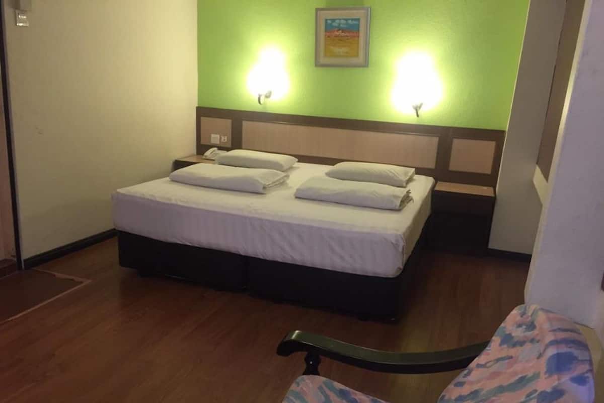 A hotel room with a bed, two bedside lamps, a chair, and a framed picture on the wall.