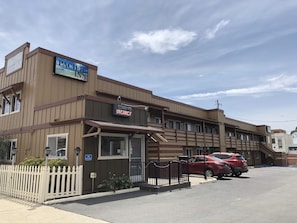 A Pacific Inn with a 'Sorry, No Vacancy' sign, a van-accessible entrance, and a parking area with a red car.