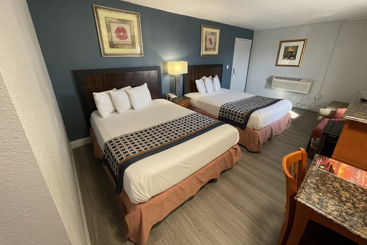 A hotel room with two beds, a desk, and a chair.