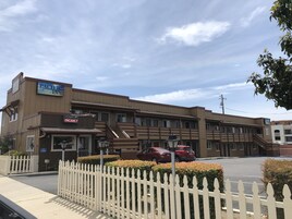 Un edificio de dos pisos con un letrero que dice 'Pacific Inn' y un letrero que indica 'No hay habitaciones disponibles'.