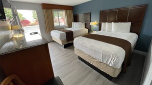 A hotel room with two beds, a desk, and a chair. - Pacific Inn (Grover Beach)