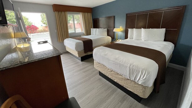 Habitación de hotel con dos camas, un escritorio y una silla.