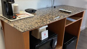 Una kitchenette equipada con microondas, cafetera y televisor sobre la encimera.