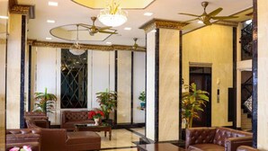 A lobby with leather sofas, a chandelier, and a ceiling fan. - Land Royal Residence Pattaya (Pattaya)