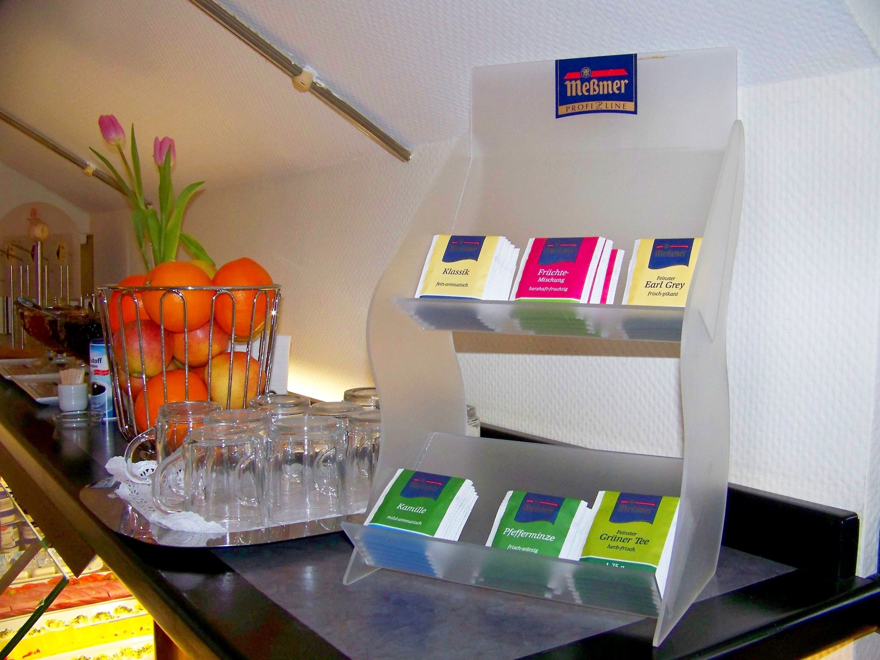 A buffet area with a fruit bowl, a tray of glasses, and a display of packaged food items.