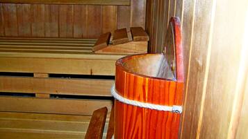 En sauna med træbænke og en træspand med rebhåndtag.