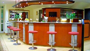 Una zona de bar con una barra curvada, varios taburetes y una pantalla de televisión sobre la barra.