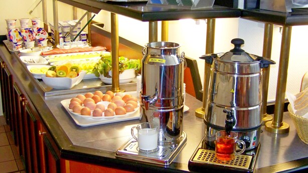 Un mostrador de buffet con diversas opciones de comida, entre ellas frutas, huevos y bebidas.