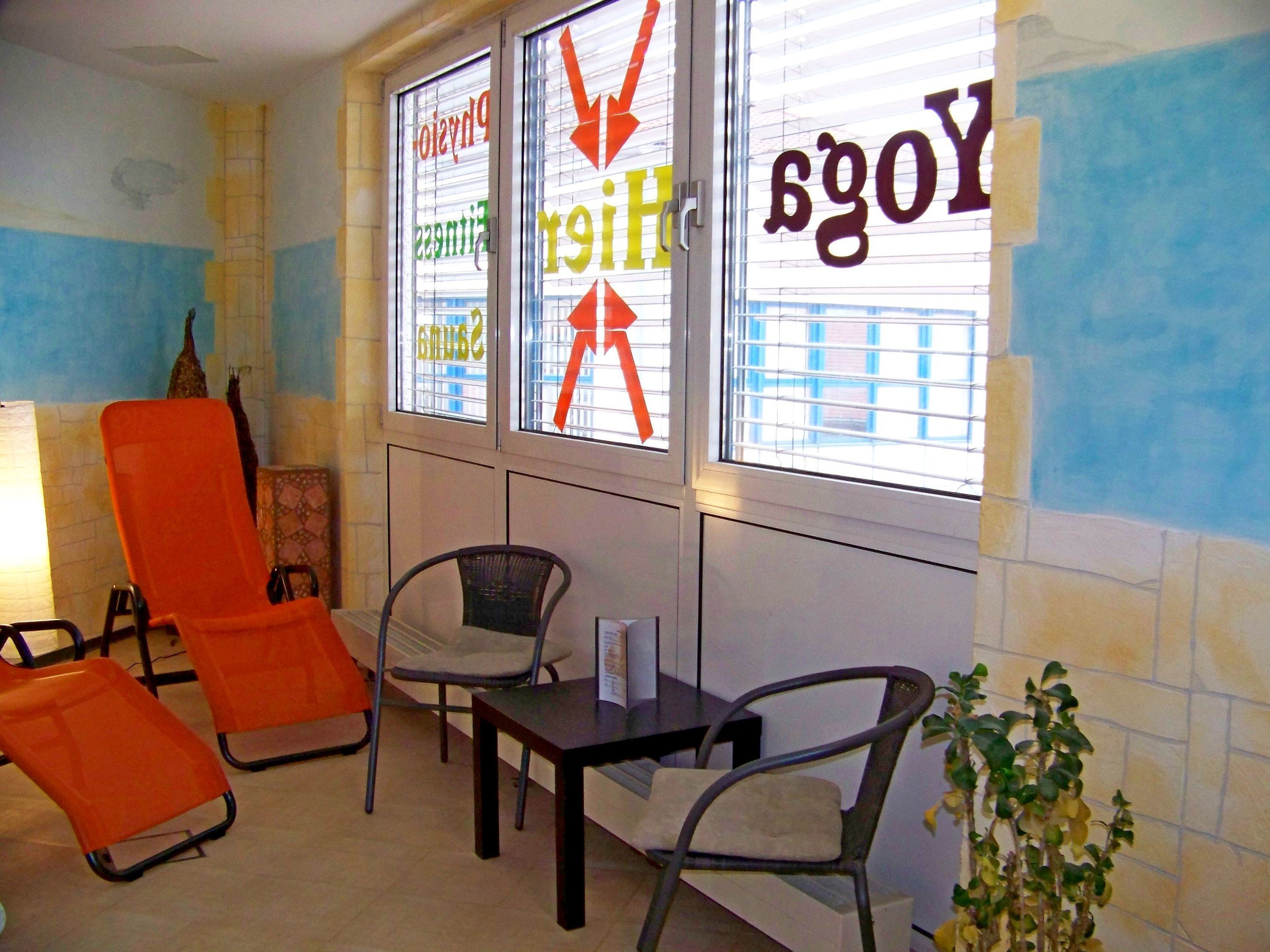 A room with two orange chairs, a small table, and a potted plant.