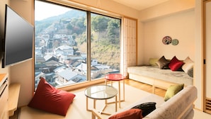 A spacious living room with a large window offering a view of a town and hills. - Kotohira Grand Hotel Sakuranosho (Kotohira)