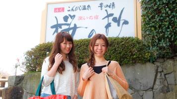Two women standing in front of a sign with Japanese characters.