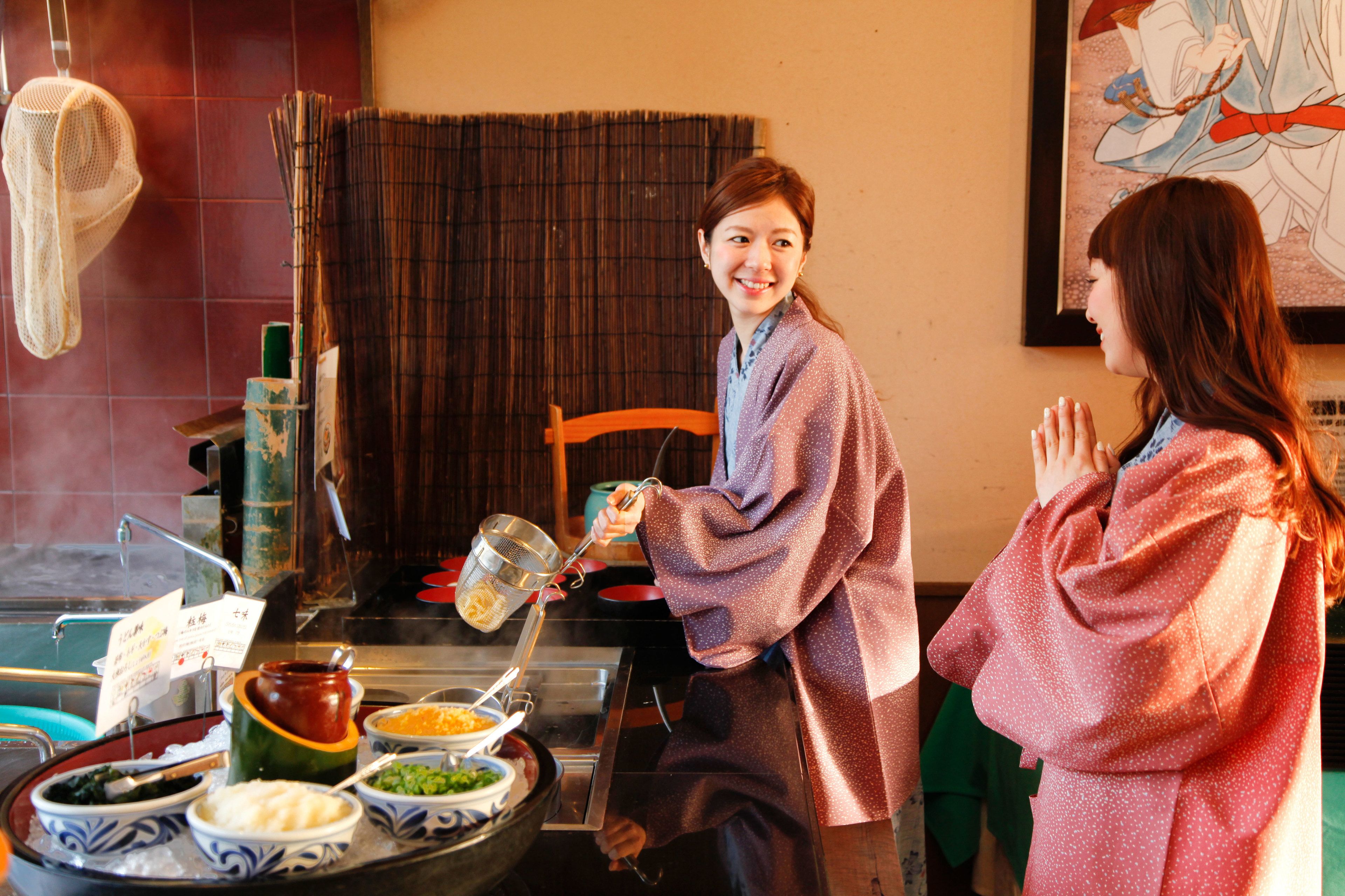 A dining area with a buffet setup, including various dishes and a strainer being used.