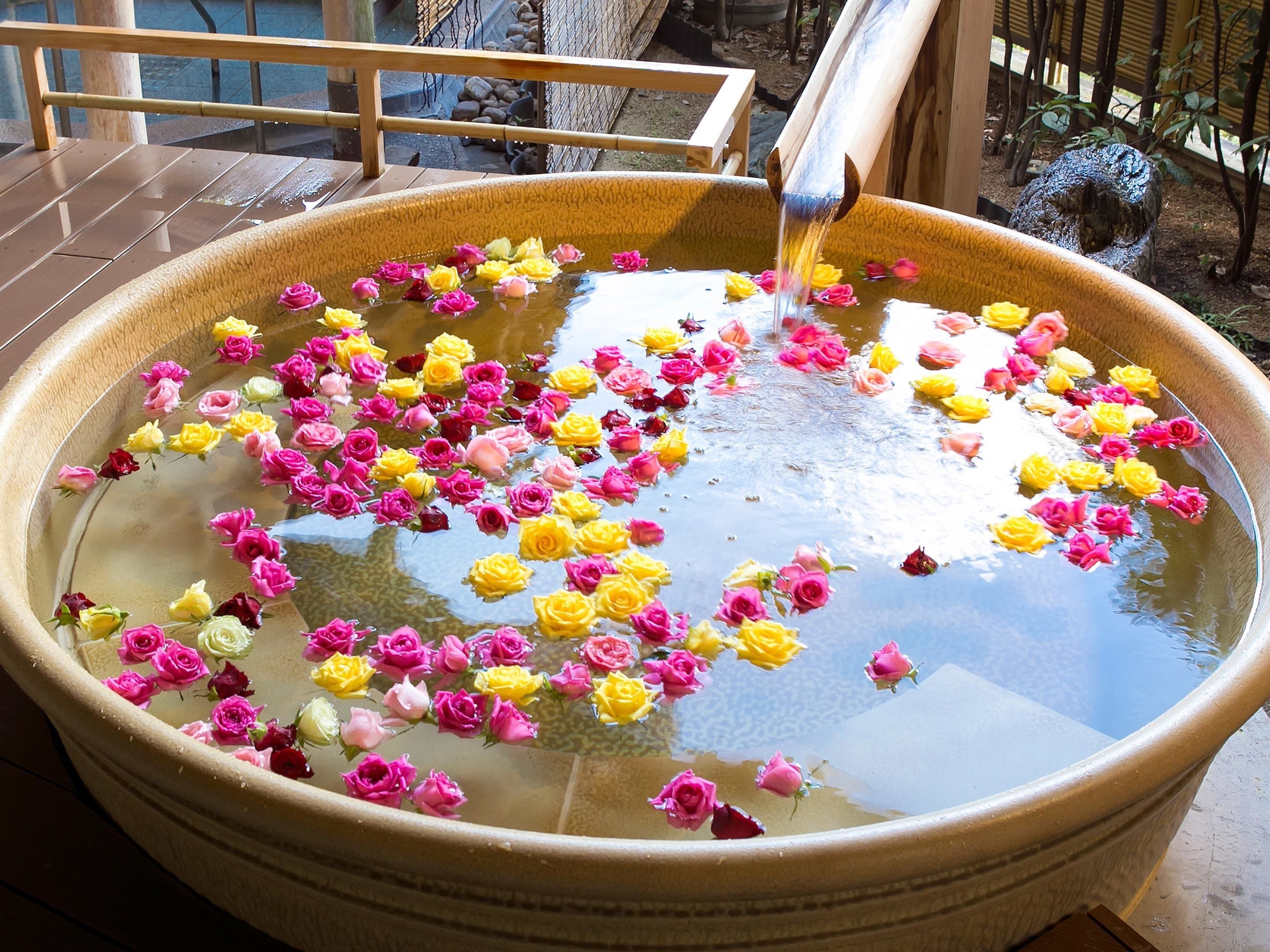 Una cuenca de cerámica grande llena de agua y flores flotando.