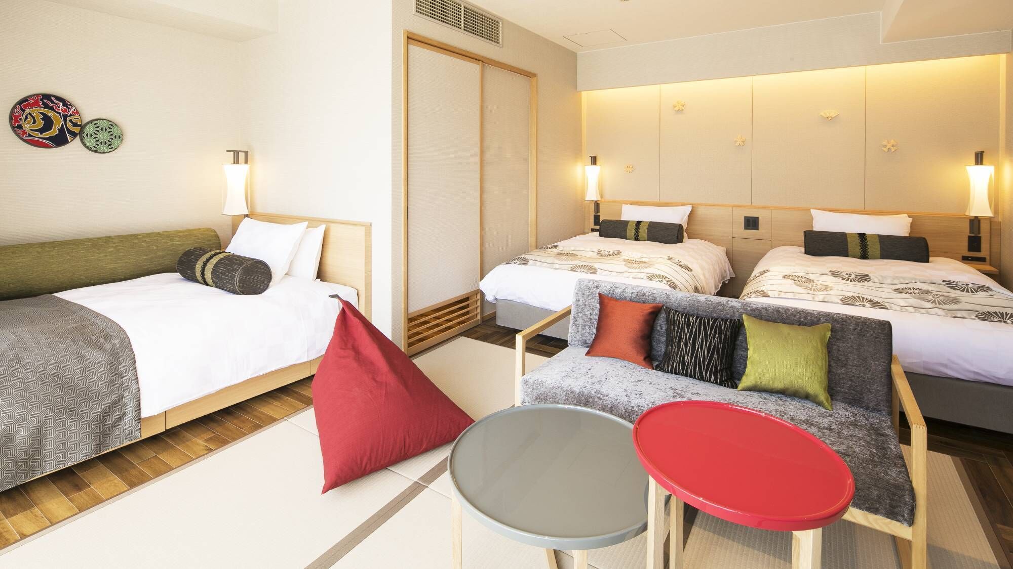 A hotel room with two beds, a small table, and a chair.