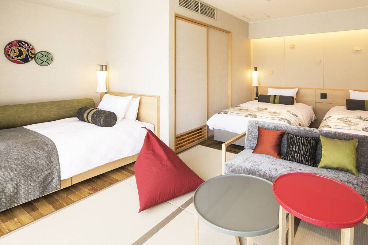 A hotel room with two beds, a small table, and a chair.