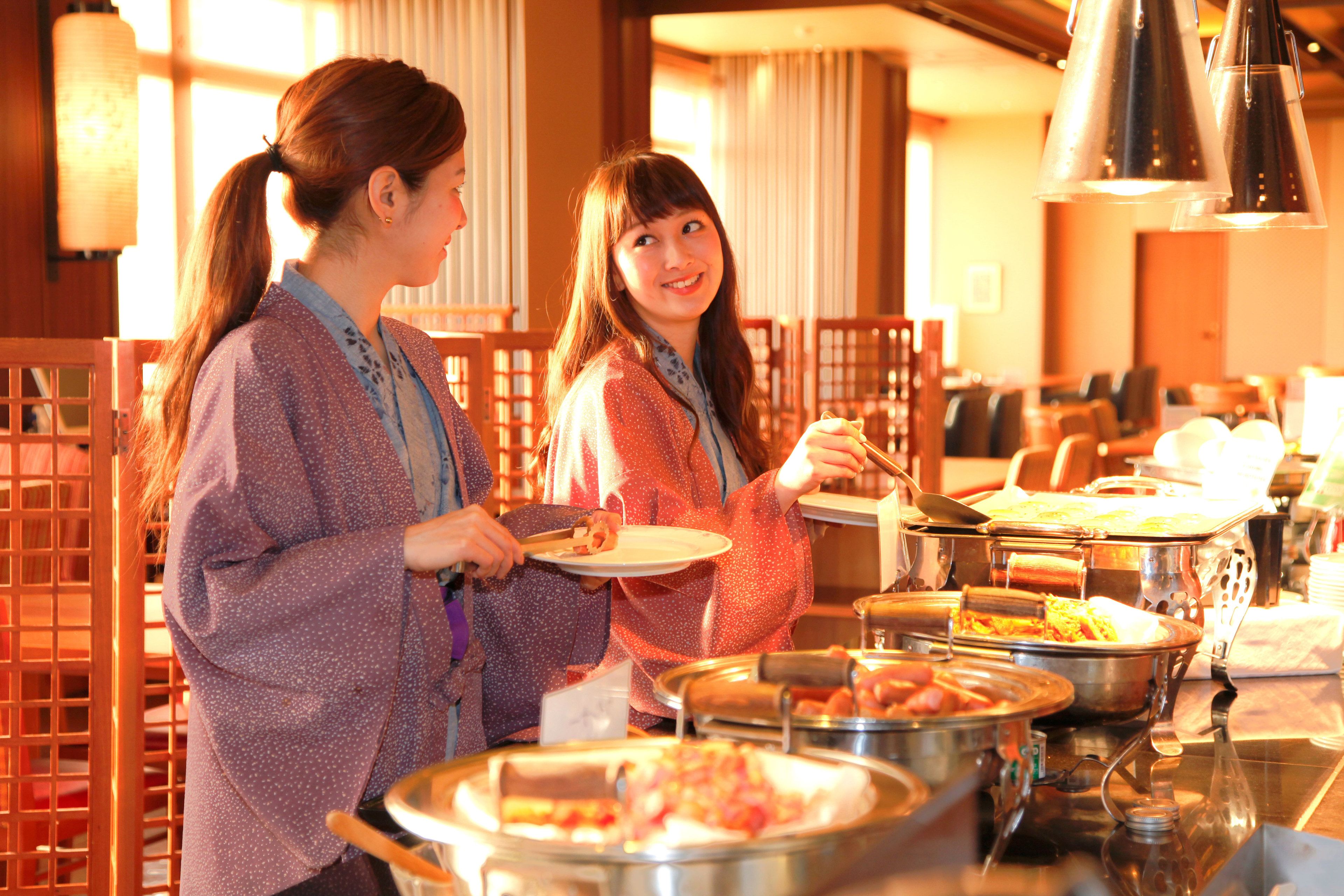 Un montaje tipo buffet con diferentes alimentos y una zona de estar con sillas de madera.