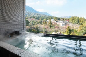 A hot spring area with a view of a mountainous landscape and traditional buildings.