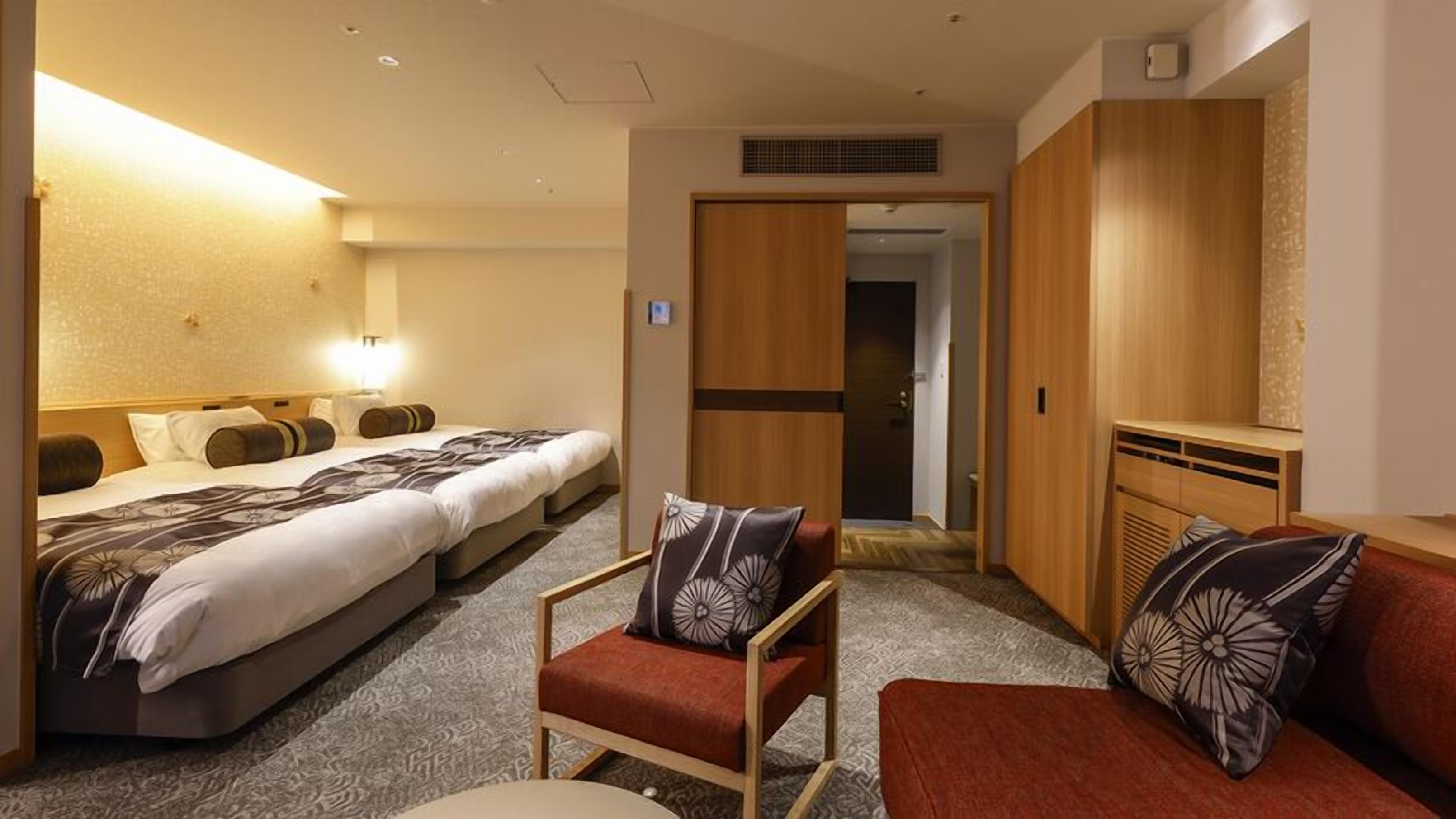 Une chambre d’hôtel comprenant un lit, une chaise, un canapé, un bureau et une armoire.