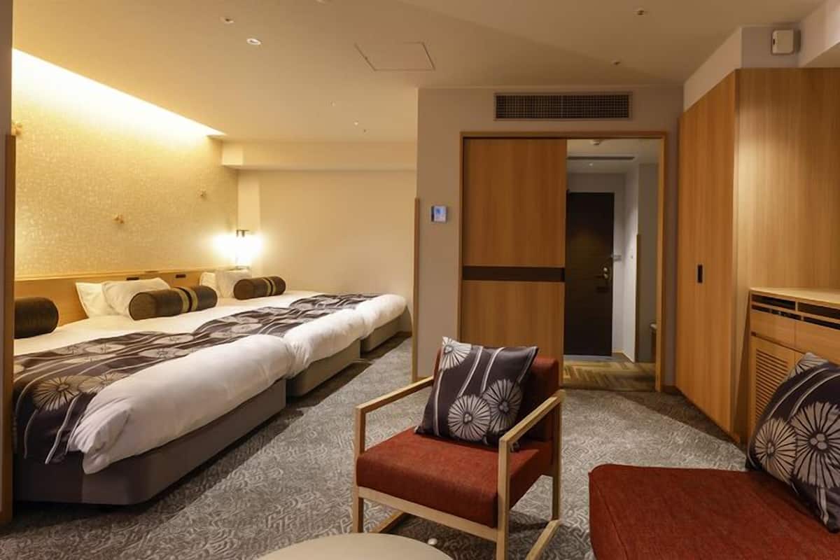 Une chambre d’hôtel comprenant un lit, une chaise, un canapé, un bureau et une armoire.