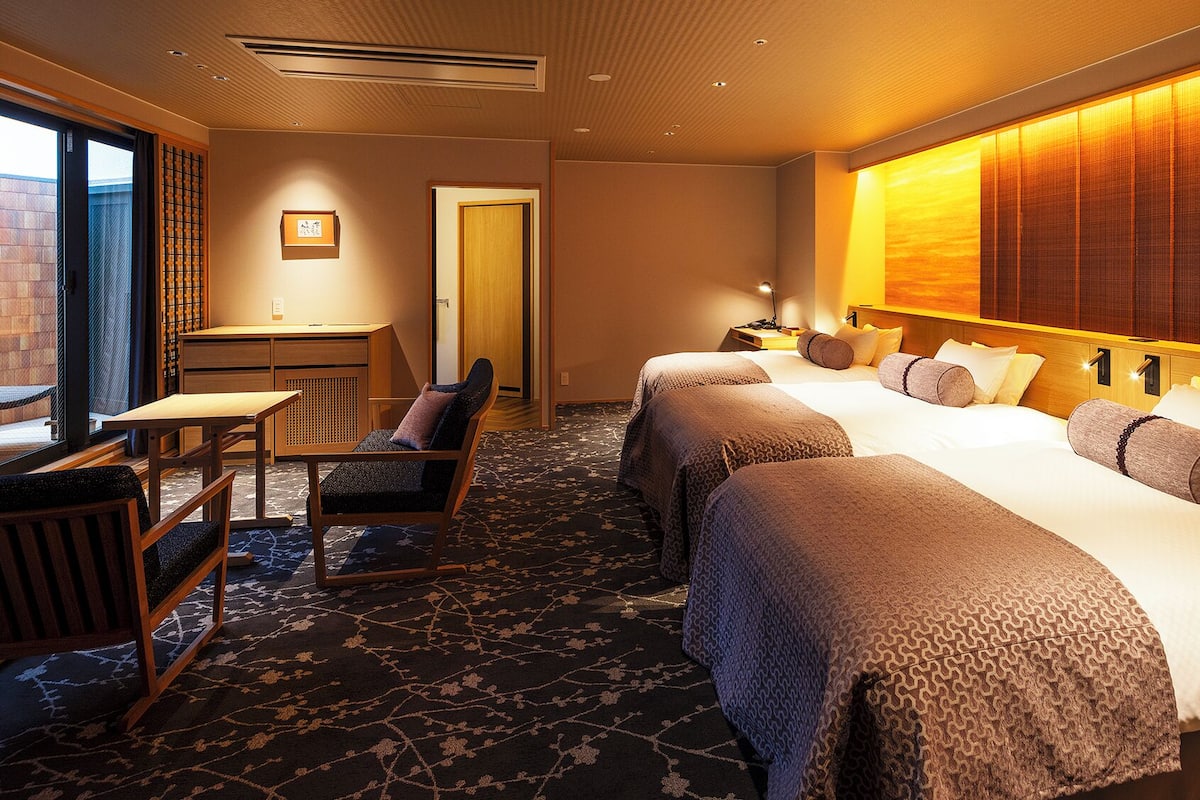 Une chambre d’hôtel avec un lit, un bureau, une chaise et une vue sur l’extérieur.
