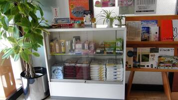 A reception area with a plant, a glass display case with various items, and a shelf with books and magazines.