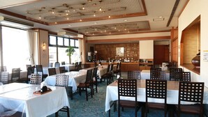A restaurant with multiple tables and chairs, a bar area, and a view of the outside.