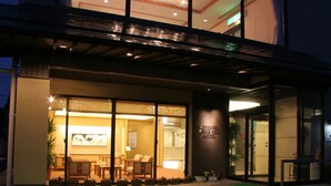 A hotel entrance with a reception desk, seating area, and a sign indicating the hotel name.