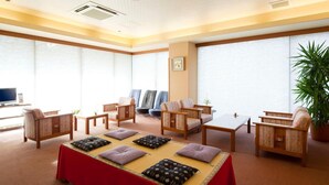 A spacious room with a large bed, multiple chairs, a television, and large windows.