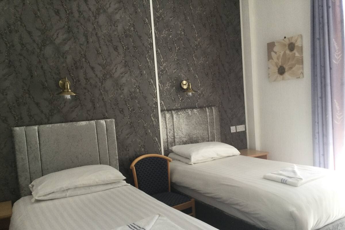A hotel room with two beds, marble-patterned walls, and a decorative wall piece.