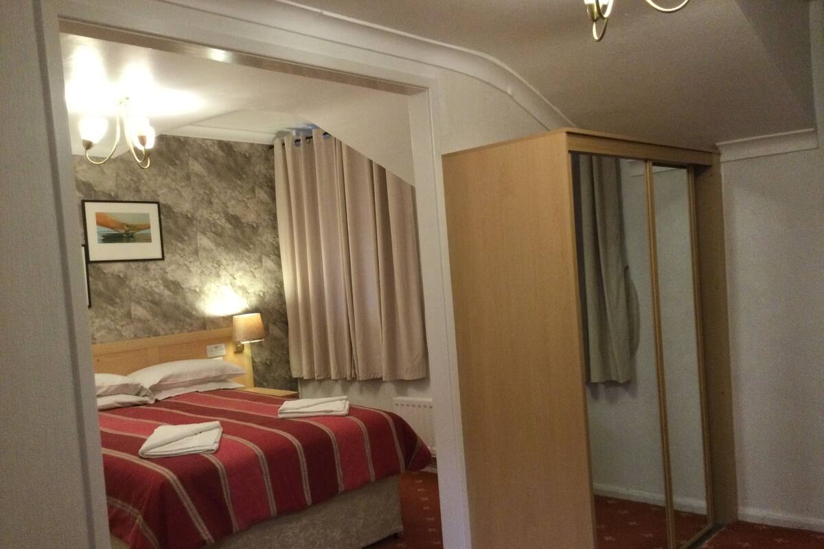 A hotel room with a bed, a bedside lamp, a mirror, and a wardrobe.