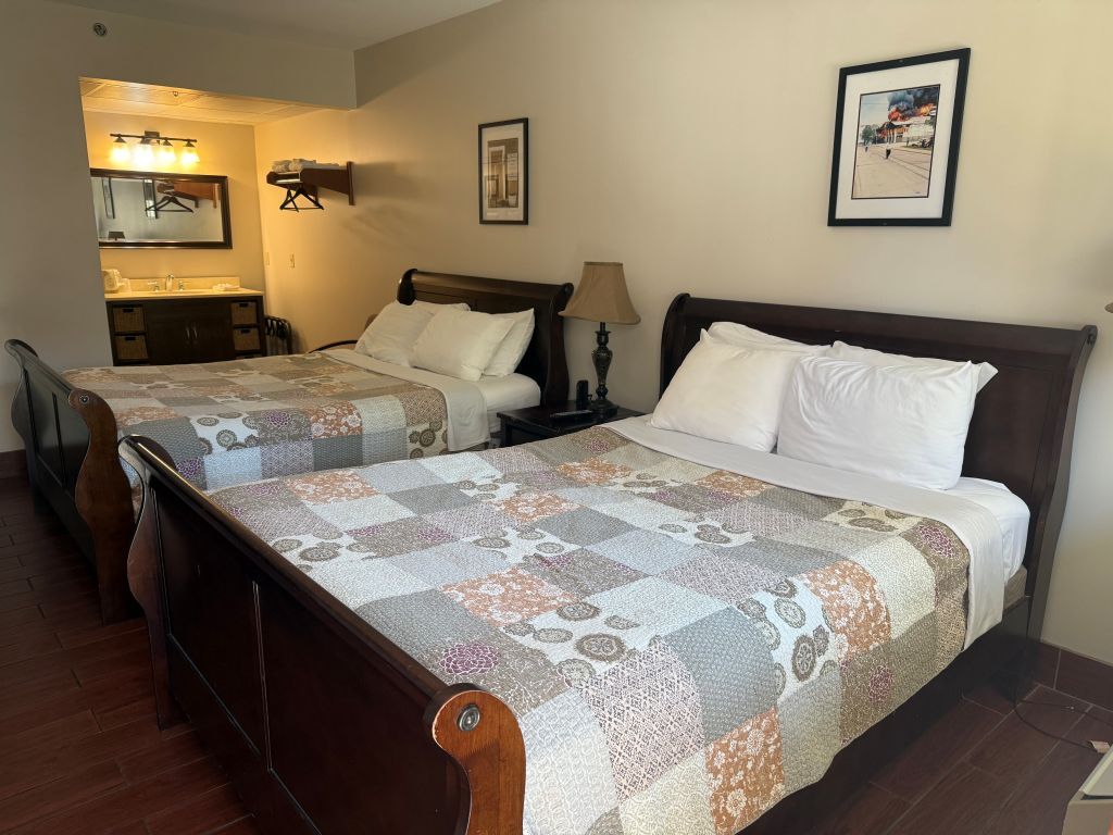 A hotel room with two beds, a bathroom, and a small sitting area.