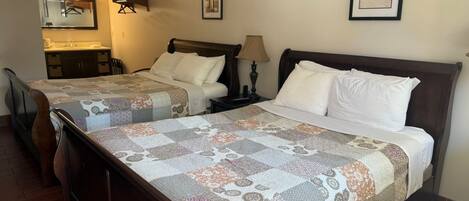 A hotel room with two beds, a bathroom, and a small sitting area.