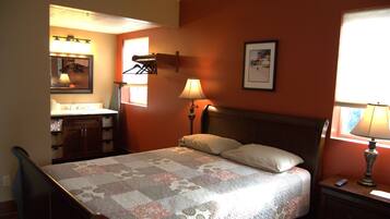 A bedroom with a bed, bedside tables, a nightstand, a dresser, a mirror, and a window.