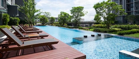 A modern hotel pool area with sun loungers and a clear blue pool.