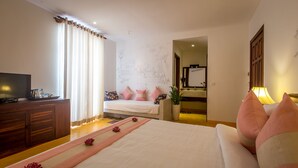 A hotel bedroom with a bed, a TV, a desk, and a bathroom visible through an open door. - VMANSION Boutique Hotel (Phnom Penh)