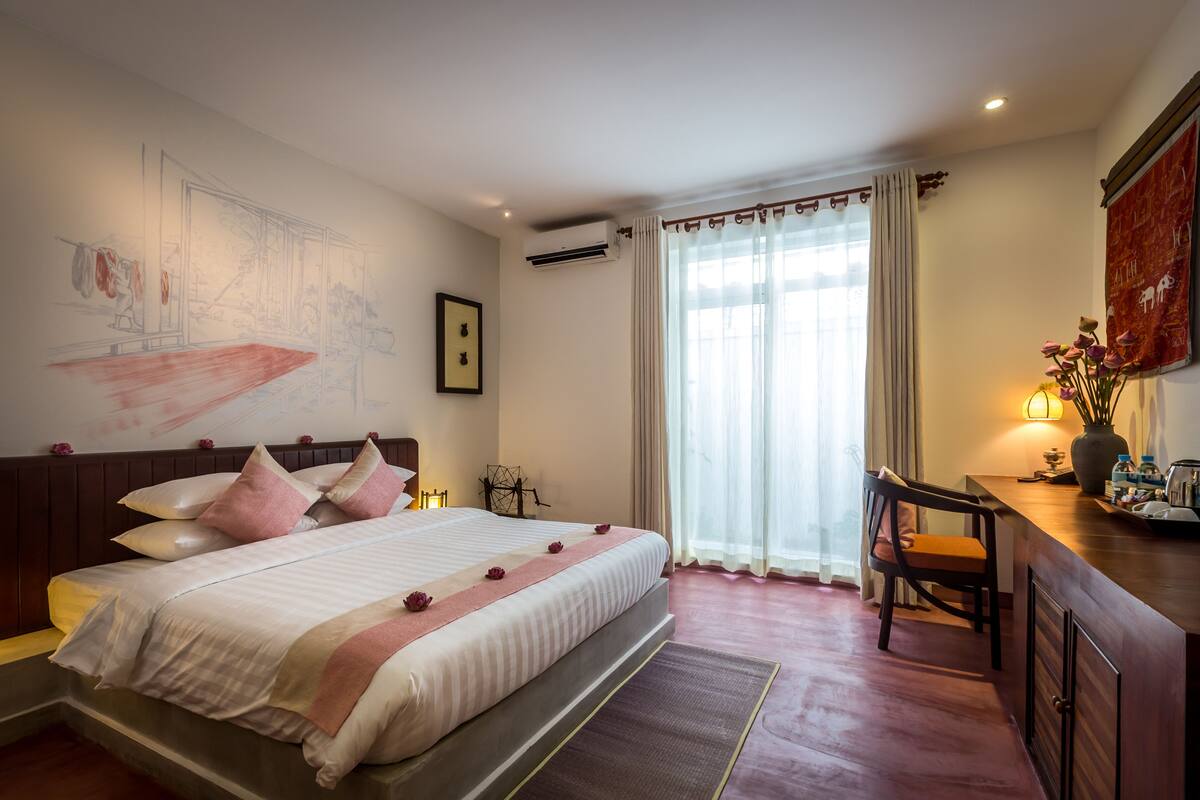 A hotel room with a large bed, a desk, and a chair.